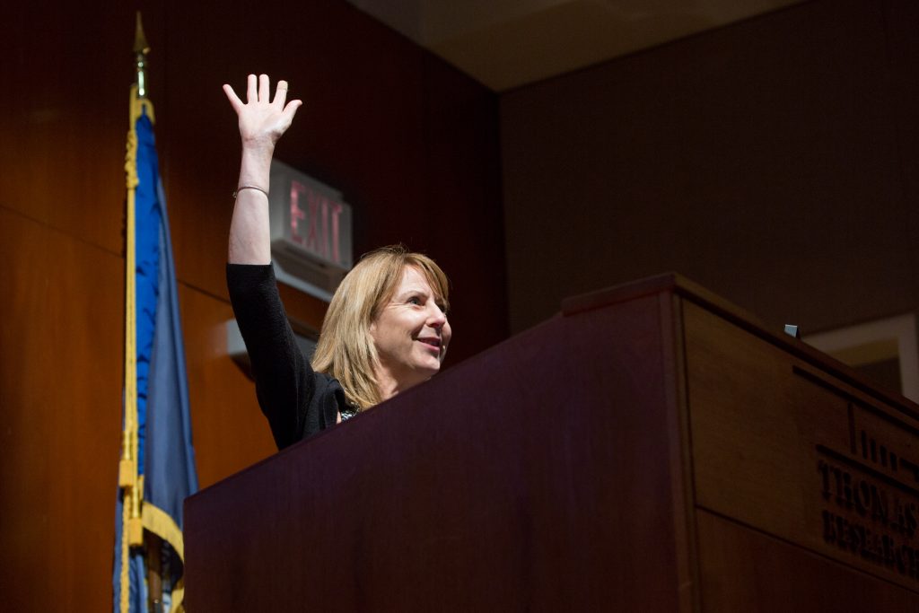 A woman raising her hand at a podium