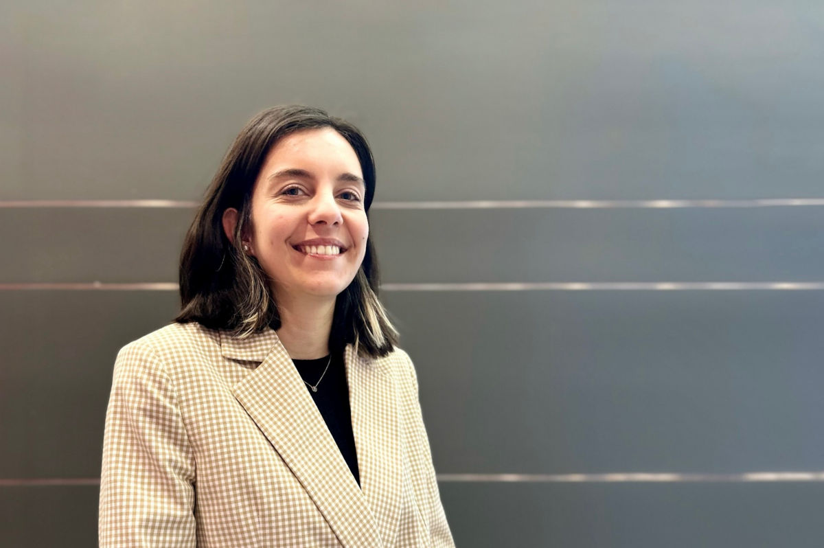 A woman smiles at the camera in front of a gray background.