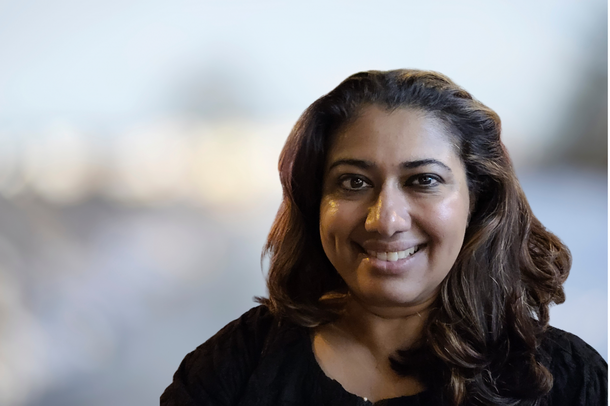 A woman in a black shirt smiles at the camera.